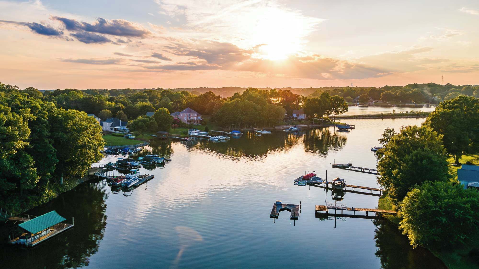 Un port de plaisance où sont amarrés des bateaux, entouré d’arbres et de maisons.