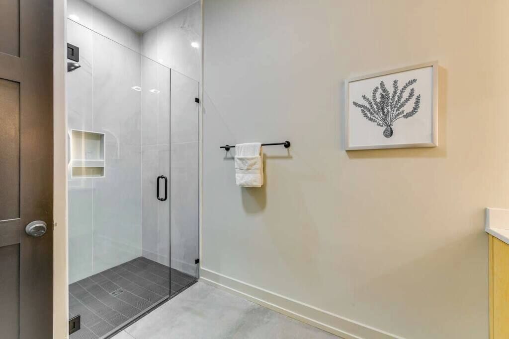 Une salle de bain moderne avec une douche à parois de verre, un porte-serviettes et une œuvre d’art encadrée au mur.