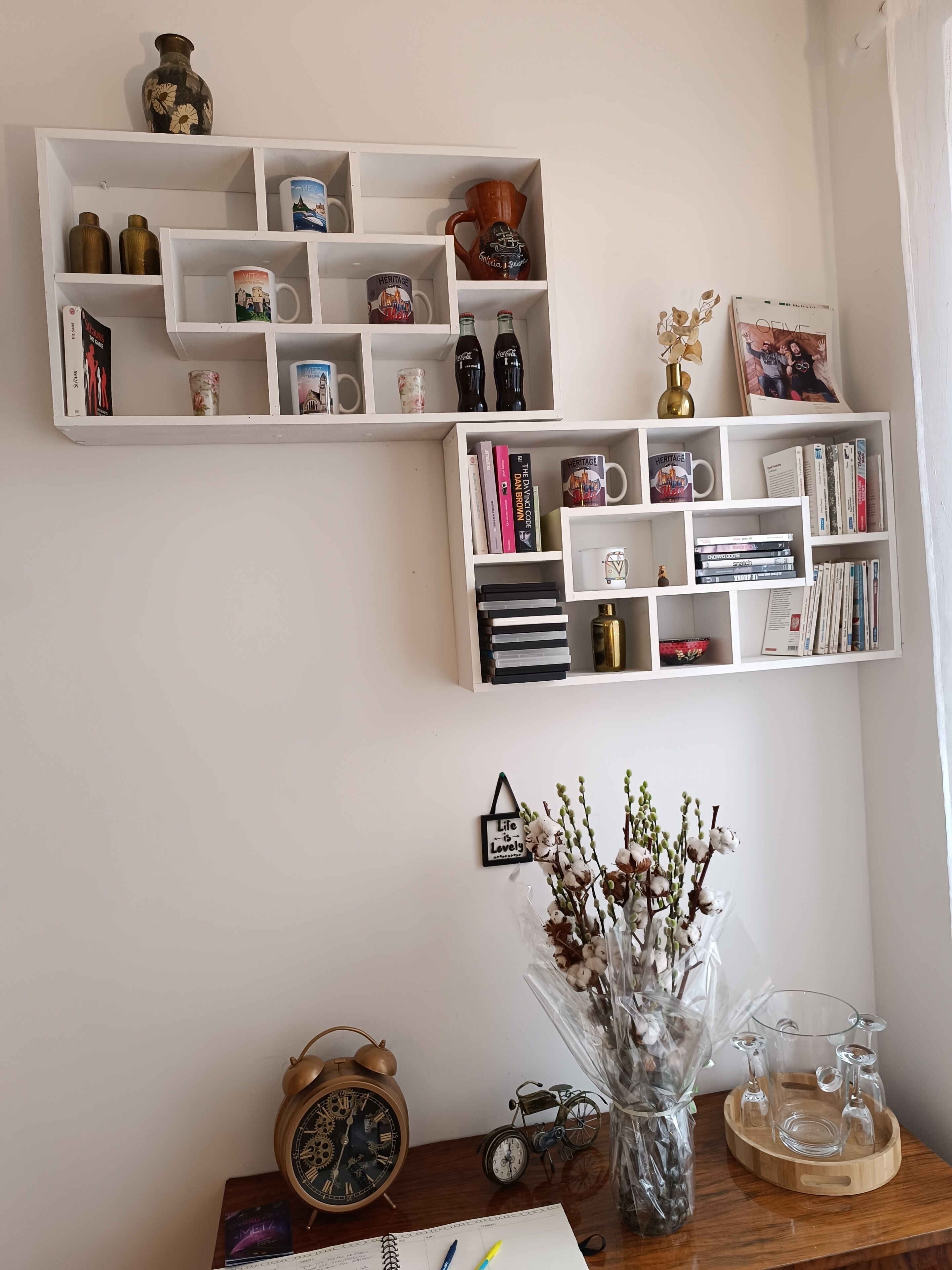 A bookshelf with decorative items, a clock, and a vase with flowers.