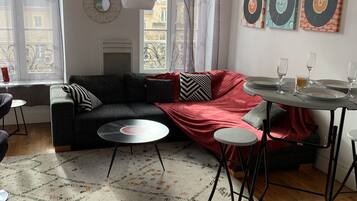 A modern living room with a sectional sofa, a small round table, and a dining area with a table and chairs.
