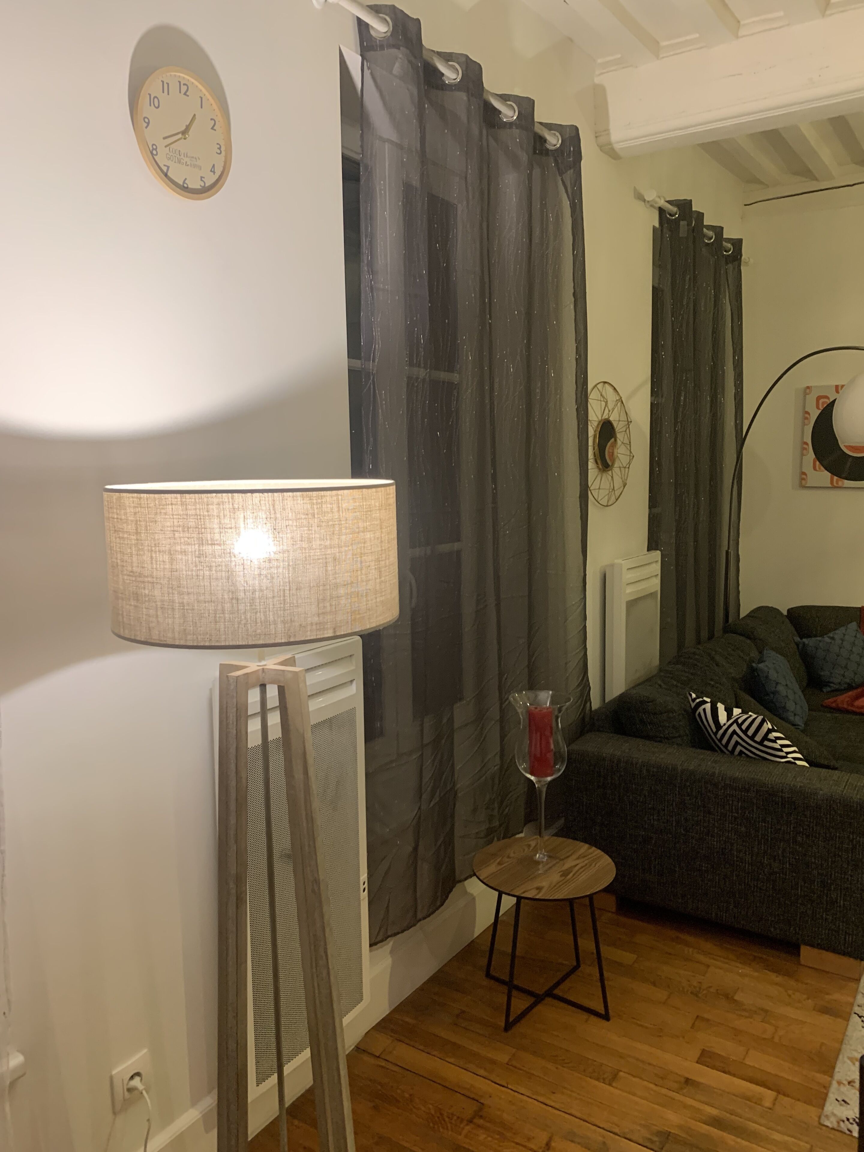 Ein Wohnzimmer mit einer Couch, einer Lampe, einer Karaffe und einer Wanduhr.