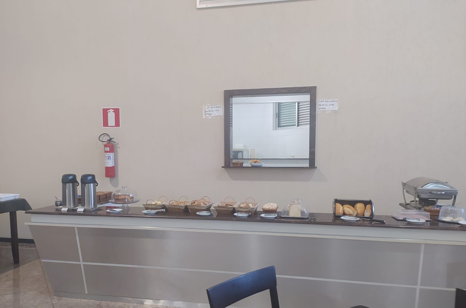 A breakfast bar with various food items, a fire extinguisher, and a mirror on the wall.