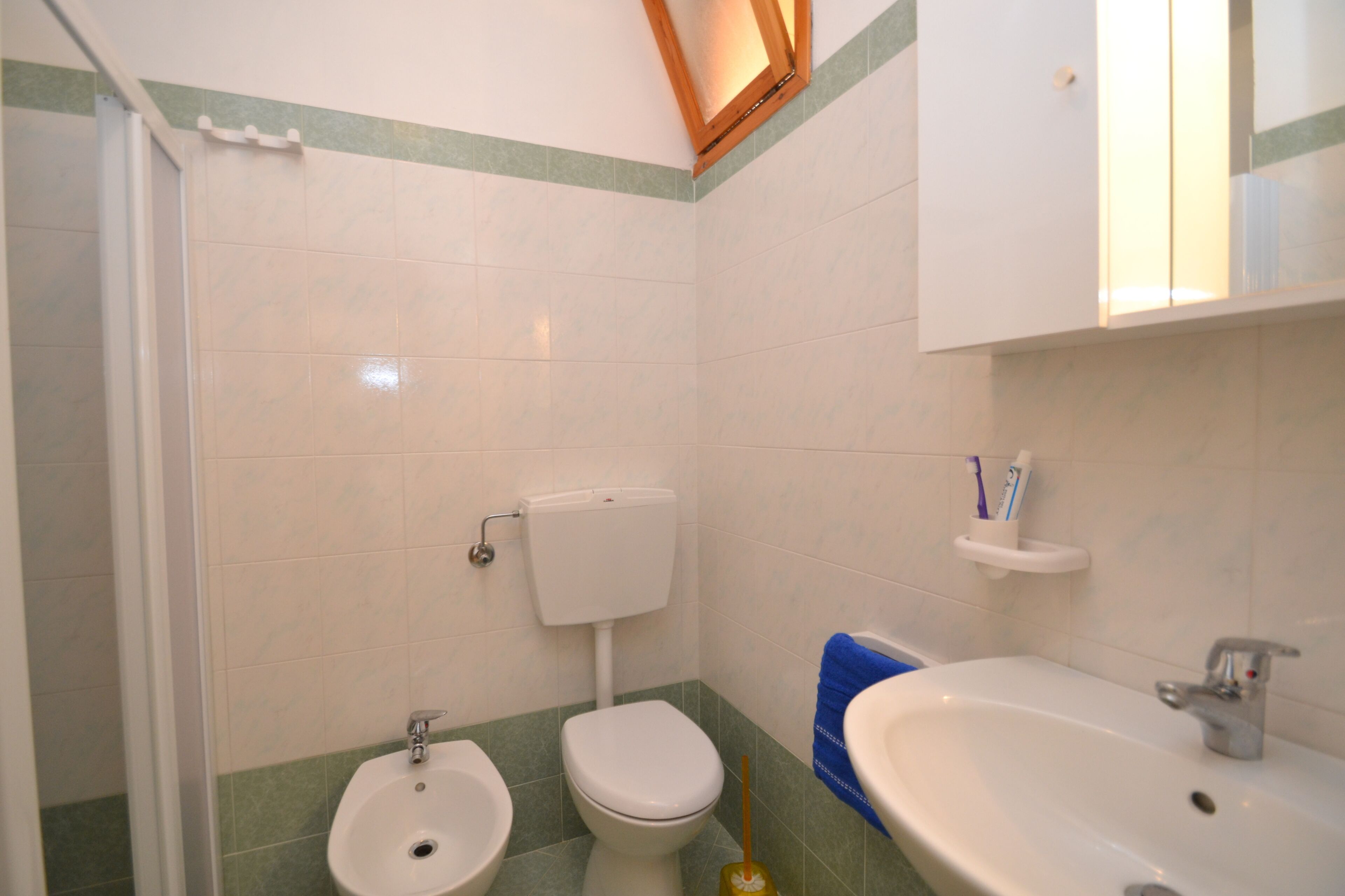 Une salle de bain équipée de toilettes, d’un bidet, d’un lavabo et d’un miroir.