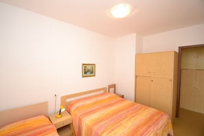 Una camera da letto con due letti, un comodino con una lampada, un armadio e un quadro appeso al muro.