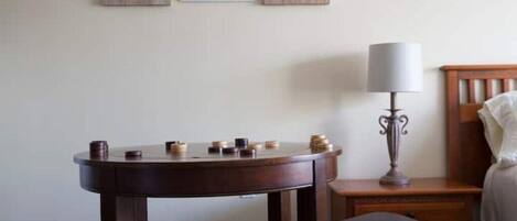 A room with a wooden table, two black leather chairs, a lamp, and three framed pictures on the wall.