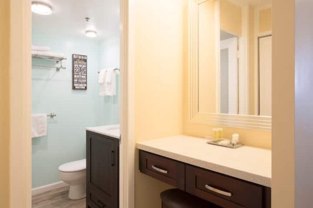 Ein Badezimmer mit Toilette, Dusche, Waschtisch mit Spiegel und einem Schild an der Wand.