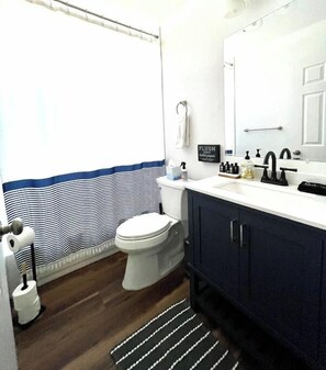 A bathroom with a toilet, a sink, a mirror, and a shower curtain. - Remodeled 4BR near Maidu Park · Roseville/Granite Bay · Pets OK (Roseville)