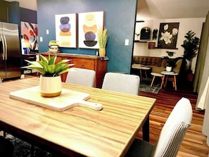 A dining area with a wooden table, chairs, and a central plant.
