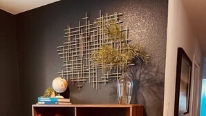 Een houten boekenkast tegen een donkere muur, met een geometrisch kunstwerk erboven.