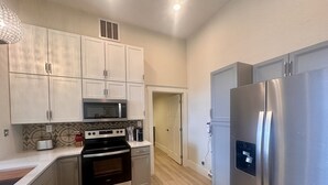 A modern kitchen with stainless steel appliances, white cabinetry, and a patterned backsplash. - Opera House Suite 1 (Kemmerer)