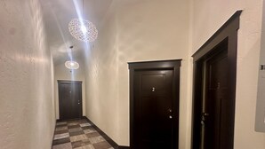 A hallway with checkered flooring, two dark doors, and hanging spherical light fixtures. - Opera House Suite 1 (Kemmerer)