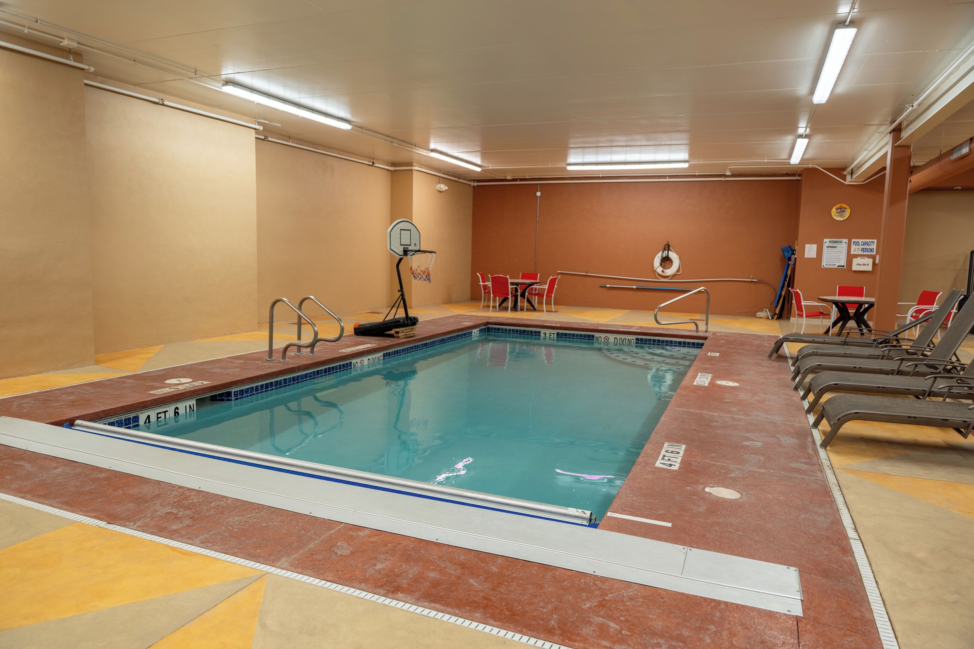 Ein Hallenbad mit Basketballkorb, roten Stühlen und einem Tisch.