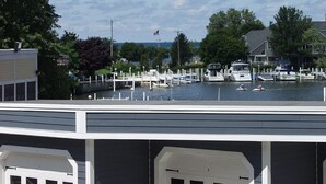Ein Yachthafen mit vertäuten Booten, einer Flagge und Blick auf das Wasser und die umliegenden Bäume.