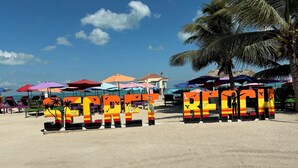 A beach with colorful umbrellas and beach chairs. - Enjoy Secret Beach sunsets, fully equipped 3bd house, large deck, AC, WiFi,  (San Pedro)