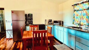 A compact kitchen with a refrigerator, microwave, coffee maker, and a small dining table with chairs. - Enjoy Secret Beach sunsets, fully equipped 3bd house, large deck, AC, WiFi,  (San Pedro)