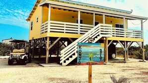 A yellow building with a balcony and a sign that reads "KONJO BETA Est. 2024". - Enjoy Secret Beach sunsets, fully equipped 3bd house, large deck, AC, WiFi,  (San Pedro)