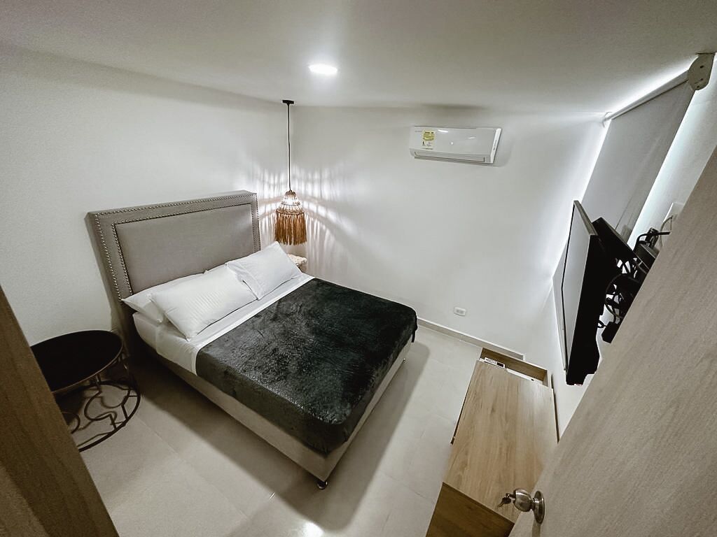 Ein Schlafzimmer mit einem Bett, einer Hängelampe, einer Klimaanlage und einer Holztür.