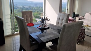 A modern living room with a dining area, large windows offering a city view, and a sofa with a patterned cover. - Habitación floridablanca 1 o 2 personas  (Floridablanca)