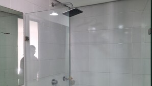 A glass-enclosed shower with a handheld showerhead, a visible soap dispenser, and a door with a handle. - Habitación floridablanca 1 o 2 personas  (Floridablanca)
