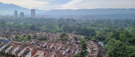 A residential area with terraced houses, a clear sky, and distant high-rise buildings.