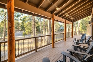 A covered outdoor area with wooden flooring, a railing, and seating. - Serenity Retreat: Near Mt. Bachelor with Pool, Spa, River & Outdoor Trails (Bend)