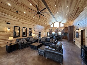 A spacious living area with a high ceiling, wooden walls, and a modern chandelier. - New Riverfront Lodge on Little Missouri River/ Crater of Diamonds & Lake Greeson (Murfreesboro)