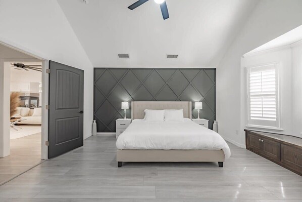 Une chambre moderne avec un grand lit, des lampes de chevet et un ventilateur de plafond.