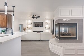 Une cuisine moderne dotée d’un îlot central, d’appareils électroménagers intégrés et de luminaires suspendus.