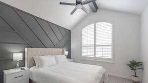 A bedroom with a bed, nightstands, a ceiling fan, a window with blinds, and a potted plant. - Contemporary Haven Retreat w/ KING BED Suite (Amarillo)