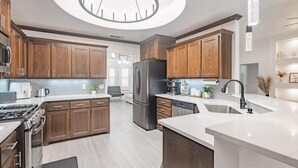 A modern kitchen with wooden cabinets, stainless steel appliances, and a central island. - Contemporary Haven Retreat w/ KING BED Suite (Amarillo)