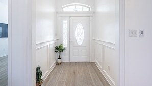 A hallway with white walls, a wooden floor, and a white door with a glass window. - Contemporary Haven Retreat w/ KING BED Suite (Amarillo)
