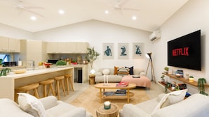 Una sala de estar moderna con un sofá, una mesa de centro y un televisor montado en la pared.