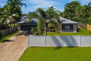 Il s’agit d’une propriété résidentielle dotée d’un garage, d’une cour clôturée et d’une grande variété de plantes tropicales.