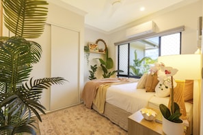 Une chambre à coucher avec un lit, une table de chevet, une lampe et des plantes en pot.
