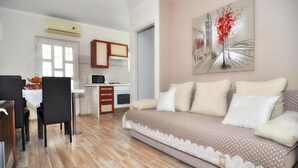 A living room with a sofa, a dining area with chairs, a kitchen with cabinets, and a painting on the wall. - Amazing apartment in Zadar (Zadar)