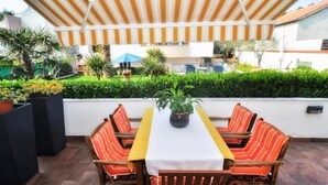 An outdoor patio with a long table and striped chairs, surrounded by greenery and a view of the neighborhood. - Amazing apartment in Zadar (Zadar)
