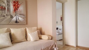 A living room with a beige sofa, a painting of a tree, and a wooden floor. - Amazing apartment in Zadar (Zadar)