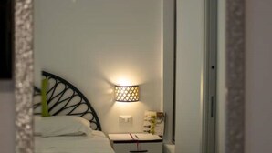 A small, neatly arranged bedroom with a single bed, a bedside table, and a wall-mounted lamp. - Room with chromotherapy shower separate entrance (Alcamo)