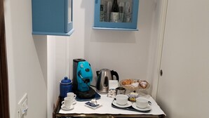 A compact kitchenette with a coffee machine, a kettle, and a small cabinet with decorative items. - Room with chromotherapy shower separate entrance (Alcamo)