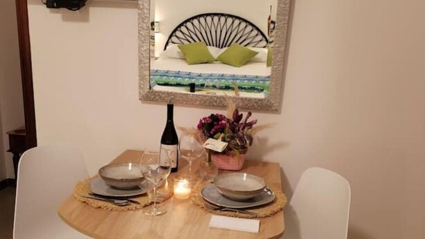 A dining table set for two with plates, glasses, a candle, and a bottle of wine. - Room with chromotherapy shower separate entrance (Alcamo)