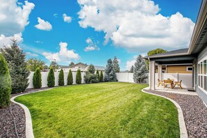 A well-maintained backyard with a lawn, a patio area with outdoor furniture, and a variety of trees. - 2 Adjacent Modern Homes • Sleep 20 • Near Top Shopping, Dining & Entertainment (Meridian)