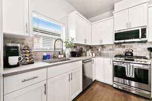 A modern kitchen with white cabinets, a coffee maker, a microwave, and an oven. - 2 Adjacent Modern Homes • Sleep 20 • Near Top Shopping, Dining & Entertainment (Meridian)