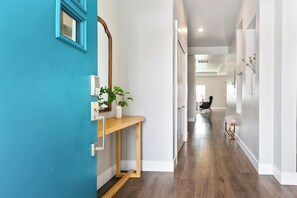 A hallway with a wooden bench, a potted plant, and a mirror on the wall.