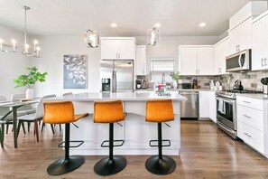 A modern kitchen with white cabinets, stainless steel appliances, and a central island with bar stools.