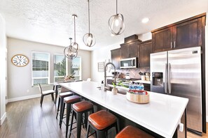 A modern kitchen with a large island, stainless steel appliances, and pendant lighting. - 2 Adjacent Modern Homes • Sleep 20 • Near Top Shopping, Dining & Entertainment (Meridian)