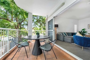 A balcony with a round table and chairs, a grey sofa, and a blue chair. - Convenient & Comfy! ~ 2Bed, 2Bath, 2Car, Balcony (Indooroopilly)