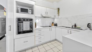 Une cuisine moderne avec des armoires blanches, un four à micro-ondes, un four et un évier.
