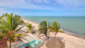 A beach view with a pool, palm trees, and a clear sky. - Casa Kibis  -  Yucatan Home Rentals (Chicxulub)