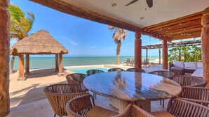 A beachside patio with a round table and wicker chairs, overlooking the ocean. - Casa Kibis  -  Yucatan Home Rentals (Chicxulub)