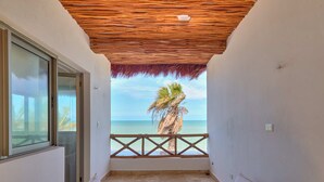 A balcony with a view of the sea and a palm tree, furnished with white chairs and teal cushions. - Casa Kibis  -  Yucatan Home Rentals (Chicxulub)